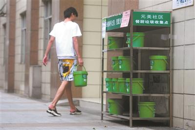 居民把厨余垃圾送到回收架。