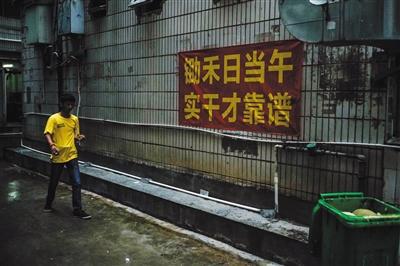 8月15日早晨7点,徐家穿过窄巷,准备去找当日的工作。三和人力市场附近的窄巷中挂了许多励志及警示标语。