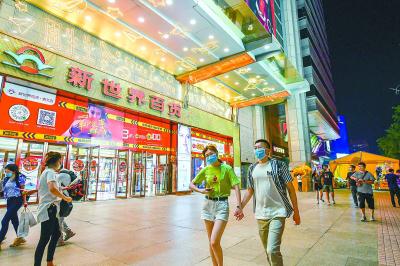 虽已到晚九点,崇文门新世界百货门前依然灯火通明,夜色不减市民消费兴致。 本报记者 邓伟摄