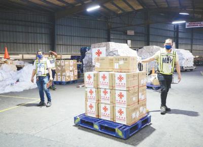  3月21日，搭载中国政府援助菲律宾医疗物资的包机抵达马尼拉国际机场。图为当地机场工作人员正在搬运物资。中国驻菲律宾大使馆供图