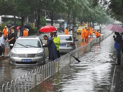 7月16日，海淀区上地十街东口，抢险人员将被淹车辆推到安全地带。