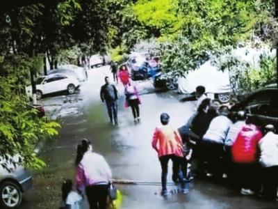小区车祸发生后,众多邻居及热心人士出手抬车救人。(监控视频)
