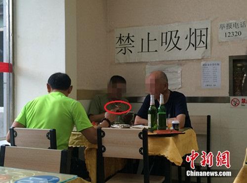 资料图:北京某餐馆,一男子在“禁止吸烟”的标识下抽烟。中新网 邱宇 摄