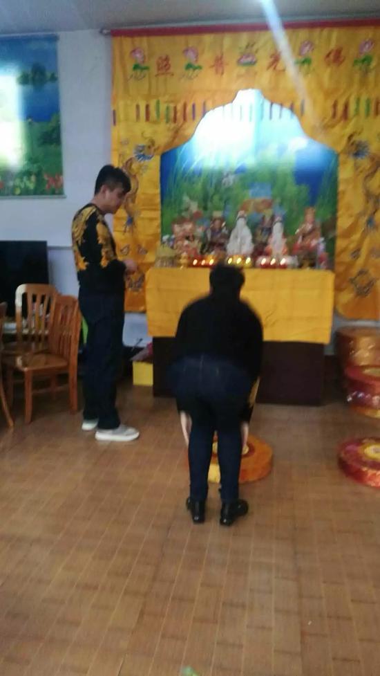 周文登(图左)让人们跪拜神像。受访者供图