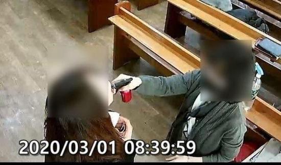 牧师夫人手持喷壶,向教徒嘴里喷盐水。