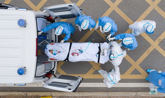  2020年3月6日，在湖北省武汉市的华中科技大学附属同济医院中法新城院区，医护人员用负压救护车转运一位新冠肺炎患者做CT检查（无人机照片）。