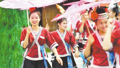 6月21日,在广西融水双龙沟森林旅游度假区梦呜苗寨,搬迁过来的苗族姑娘准备给游客表演民族舞蹈。新华社记者 黄孝邦摄