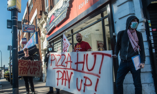 （图说：4月，南伦敦一家必胜客外卖店员工抗议雇主拖欠政府发放的补助薪金。图/Getty）