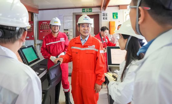 中國海油研究總院總工程師、鑽完井專家李中與工作人員在作業現場交流溝通。