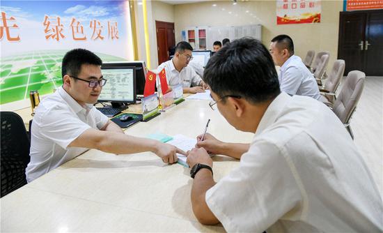 2019年7月16日,在内蒙古自治区自然资源厅的自然资源政务大厅内,办事员(左)为采矿企业办理相关审批手续。新华社记者 彭源 摄