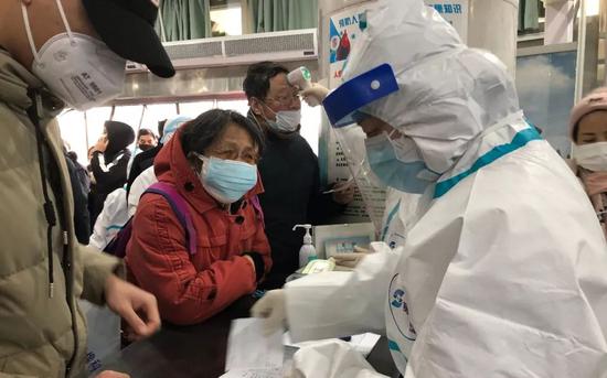 ▲1月23日,武汉红十字会医院,“全副武装”的医护人员正为患者检查体温。新京报记者 向凯 摄