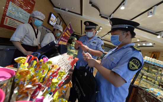 执法人员对校园周边的食杂店、小超市开展检查。通州区市场监管局供图