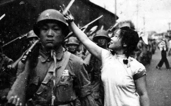 ▲杭州解放时,武林门附近,身着旗袍的纺织女工为解放军戴花