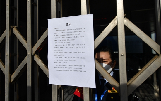 车站工作人员在门内值守，向市民解释出入口临时封闭的情况。新京报记者 王贵彬 摄