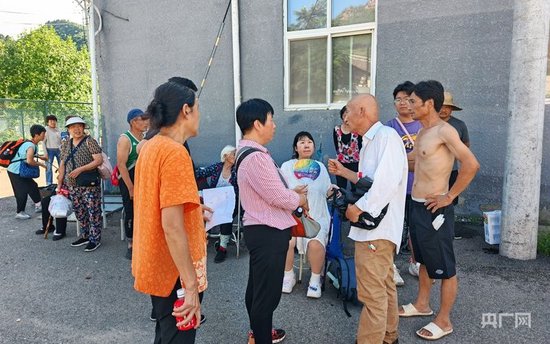 等待轉移的村民和村書記王起春(右二)說著自己家的情況(央廣網記者 龐婷 攝)