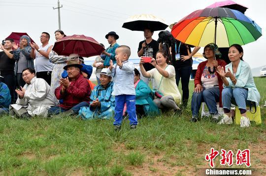 图为牧民在雨中观看乌兰牧骑演出。 翟璐 摄