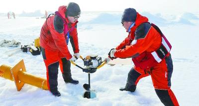 中国科考队员在冰上打孔，准备安放温度链浮标。新华社发