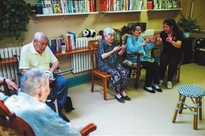 7月12日,劲松八区,社区养老驿站,护工在带领老人做游戏。