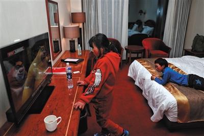 昨日，在入住的宾馆房间内，王福满和姐姐被电视里的动画片节目吸引。新京报记者 彭子洋 摄