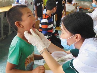 2017年夏,“北京市协作者协会”的志愿者在某打工子弟小学组织开展儿童健康体检服务。北京市协作者社会工作发展中心供图