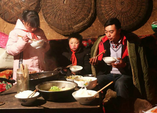 前不久在网上走红的云南鲁甸的“冰花男孩”引起了中国网民对贫困问题的关注。图为“冰花男孩”(中)与家人一同吃饭。(美国《福布斯》双周刊网站)