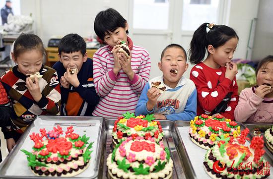 图为小朋友们在品尝村民李会青制作好的花糕。