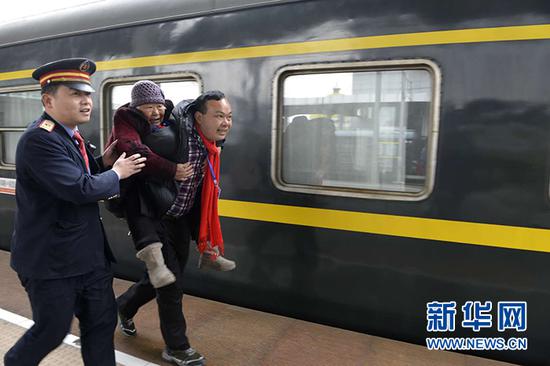  在列车工作人员的帮助下，郭春红背着母亲顺利登上车。 （郭海洋 摄）