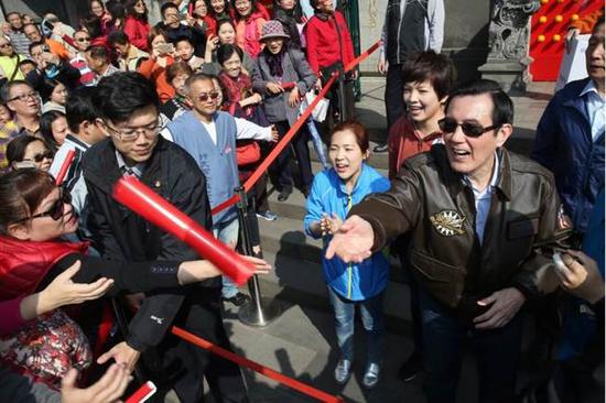 马英九发了春联半小时还是有民众没拿到,马英九把剩下的春联丢到人群中,许多民众争相把手伸出来希望接到。(图片来源:台湾《中时电子报》)
