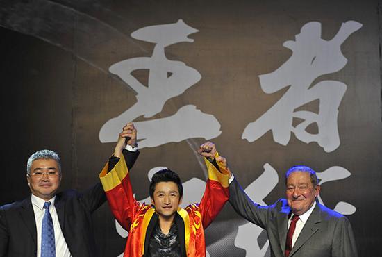 美国Top Rank公司创始人鲍勃·阿鲁姆（右）及推广公司盛力世家总裁李胜（左）一起为邹市明穿上拳击联合会的大红袍。视觉中国 资料