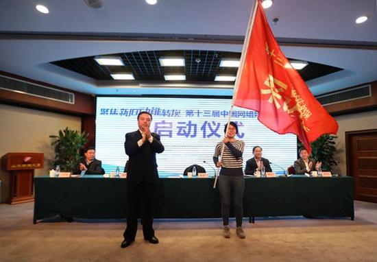 中共山东省委宣传部副部长、中共山东省委网络安全和信息化领导小组办公室主任林建宁向采访团授旗。采访团代表人民日报新媒体中心记者喻晓雪接旗。 (记者 亓翔 王宗阳 摄)