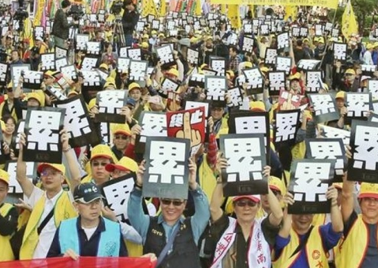 不少台湾网民认为,台湾最便宜的用品是“人力”。图为劳工团体去年12月的游行,高举标语“累”。(资料图片)