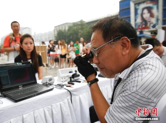 資料圖：在北京崇文門街邊舉行的寺庫奢侈品鑒寶會，吸引眾多路人排隊鑒寶。 中新社發 杜洋 攝