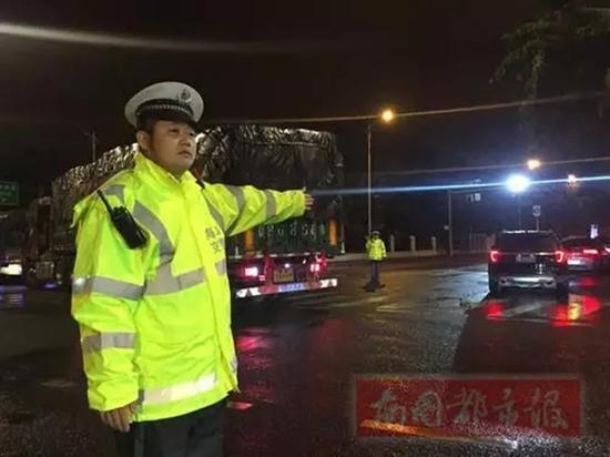 23日凌晨,执勤交警黄清顶着寒风冷雨,在路口指挥交通。南国都市报 图