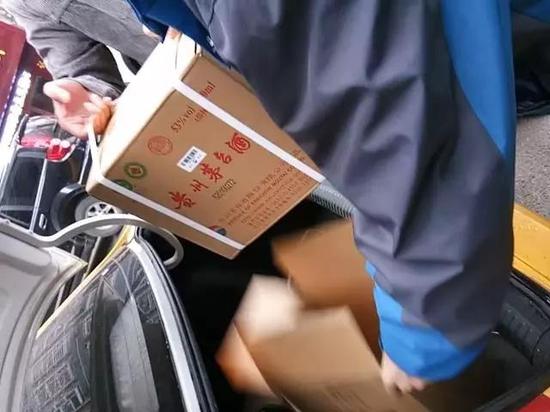 在仁怀市内的交易地点，售假者正为购买者开箱验货。