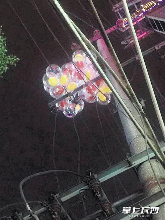 一大捧气球挂在电线杆的横梁上,取不下来了。