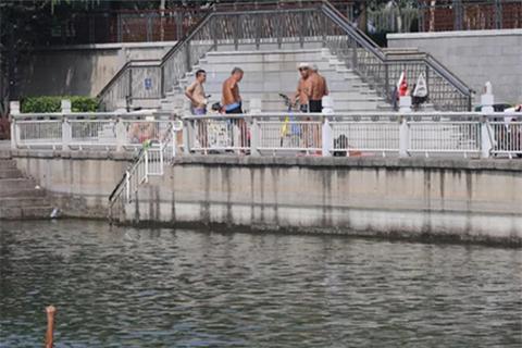 ▲8月25日，东二环护城河，几位游泳者上岸后聊天。 新京报记者 王飞 摄