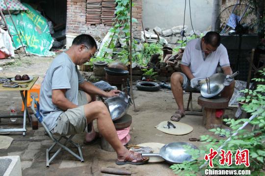 图为“双牛铁锅”品牌负责人牛祺明正在家中与亲戚一起打制铁锅。　赵晓 摄