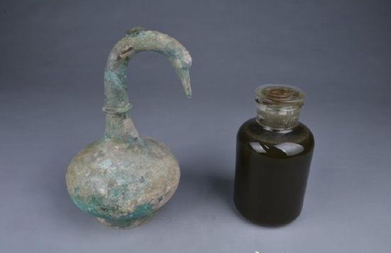 鹅首曲颈青铜壶和壶内的3升药酒。来源：三门峡市文物考古研究所官方微博
