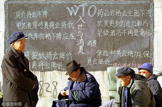 2001年12月8日，人们在一块黑板前休息。2001年11月11日，中国加入世贸组织。（资料图，图源：视觉中国）