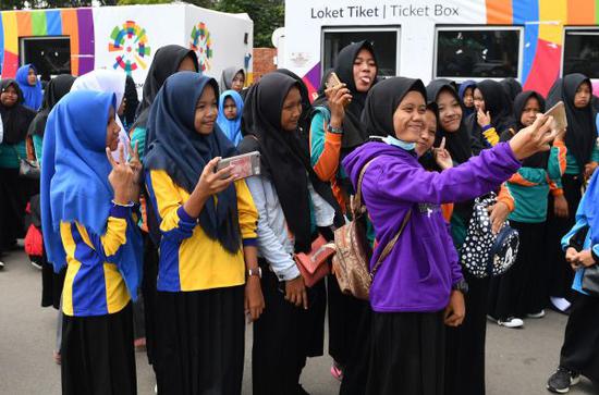 8月23日在巨港，几名女学生在亚运会售票厅欢乐自拍。（法新社）