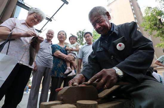 吴锦泉为社区居民磨刀(新华社)