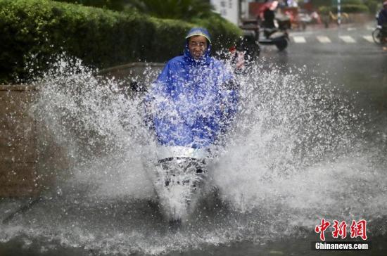 8月17日,南京街头的一名男子骑车从积水中冲过。泱波 摄