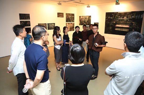 嘉宾及观众聚集在艺术家江凯群周围，聆听艺术家本人的讲解。