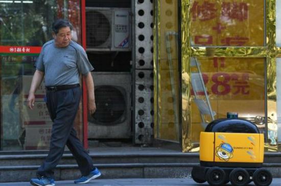 资料图：一名路人回头观察送货的机器人。（AFP）