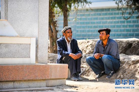艾买尔·依提生前在陵园给儿子艾尼瓦尔·艾买尔讲当年的故事（2011年4月29日摄）。 新华社记者 江文耀摄