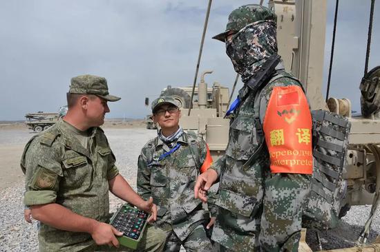 ▲俄军参赛队员正在中国翻译的协作下与解放军教练员交流。