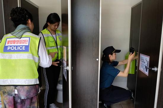 韩国女警在公共厕所里用探测仪排查偷拍摄像头。