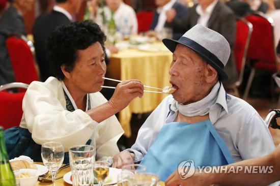 8月20日，在朝鲜金刚山酒店举办的朝韩离散家属欢迎晚宴上，现居朝鲜的70岁女儿正给现居韩国的百岁父亲喂食。