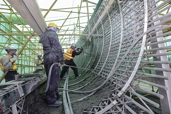 国家雪车雪橇中心施工人员在赛道模块实验段喷射水泥。