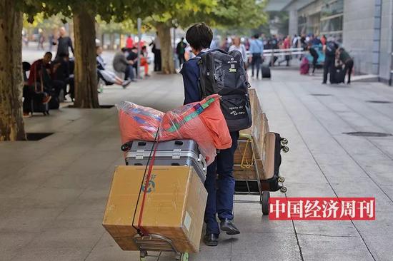 一位拖着厚重行李的旅客(《中国经济周刊》首席摄影记者 肖翊 | 摄)